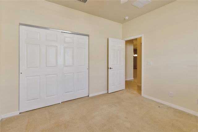 unfurnished bedroom with light carpet, a closet, visible vents, and baseboards