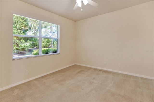 empty room with light carpet, a ceiling fan, and baseboards