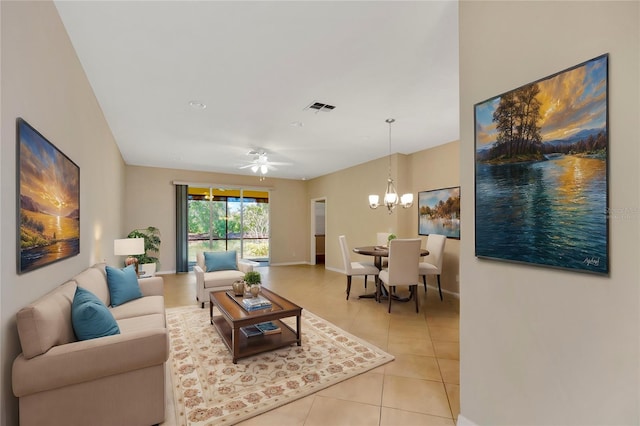 living area featuring light tile patterned floors, baseboards, visible vents, and ceiling fan with notable chandelier