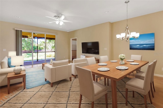 dining space featuring ceiling fan with notable chandelier, light wood-style floors, visible vents, and baseboards