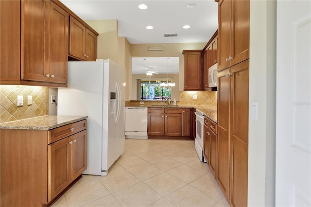 kitchen featuring light stone counters, brown cabinets, light tile patterned floors, visible vents, and white appliances