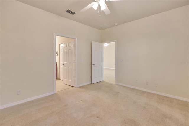 spare room with baseboards, visible vents, a ceiling fan, and light colored carpet