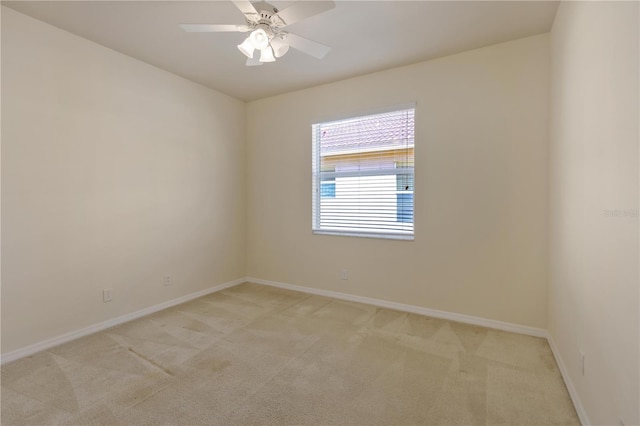 spare room featuring light carpet, baseboards, and a ceiling fan