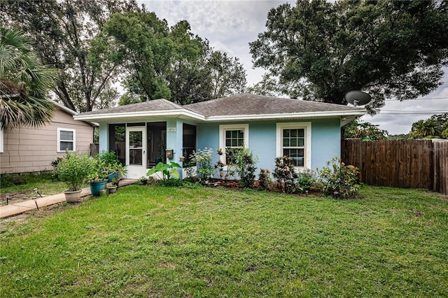 view of front facade featuring stucco siding, roof with shingles, a front yard, and fence