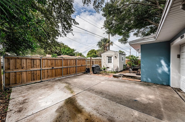 view of patio / terrace featuring an outdoor structure, a fenced backyard, and a storage shed