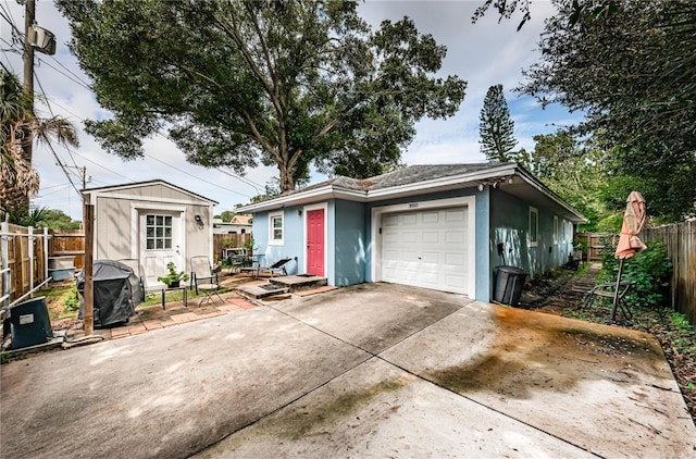 view of front of home featuring stucco siding, driveway, a fenced backyard, an outbuilding, and an attached garage