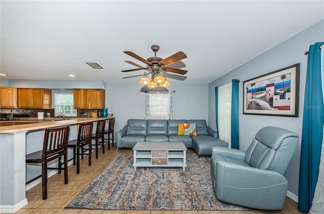 living area featuring light tile patterned flooring, baseboards, visible vents, and ceiling fan