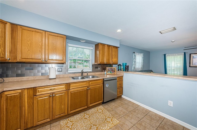 kitchen with backsplash, brown cabinets, dishwasher, and a sink