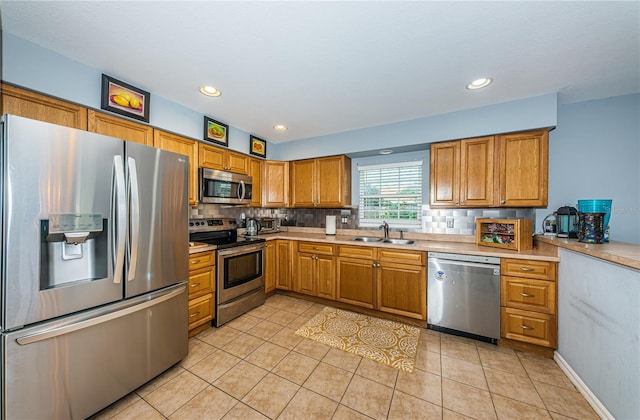 kitchen featuring a sink, decorative backsplash, light countertops, appliances with stainless steel finishes, and brown cabinets