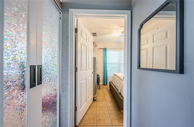 hall featuring light tile patterned flooring and visible vents