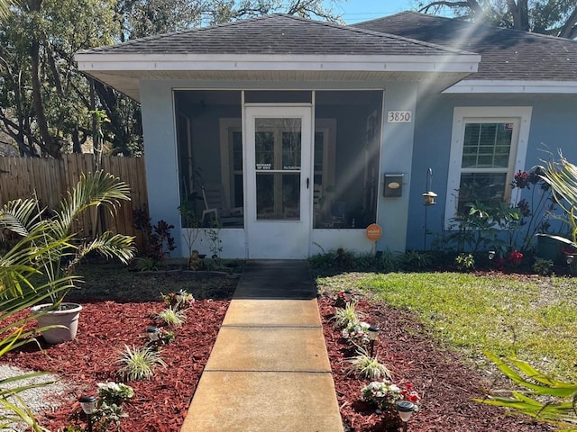 property entrance featuring fence, roof with shingles, and stucco siding