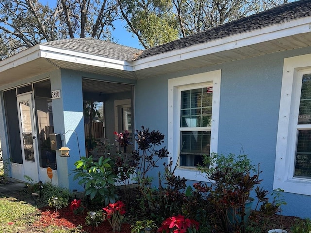 view of side of property featuring stucco siding and a shingled roof