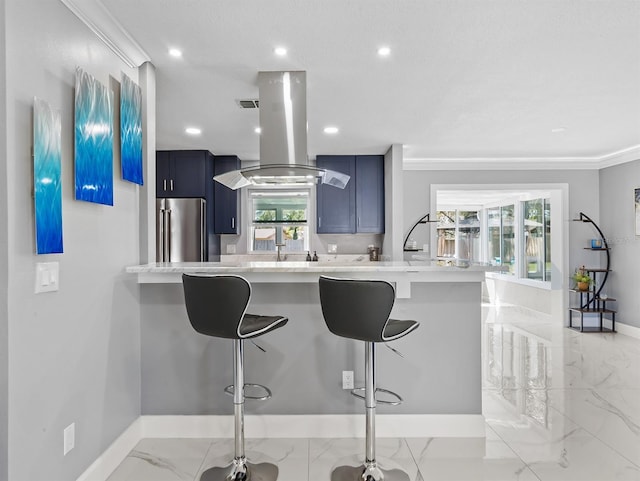 kitchen with high end fridge, light countertops, island exhaust hood, and a breakfast bar area