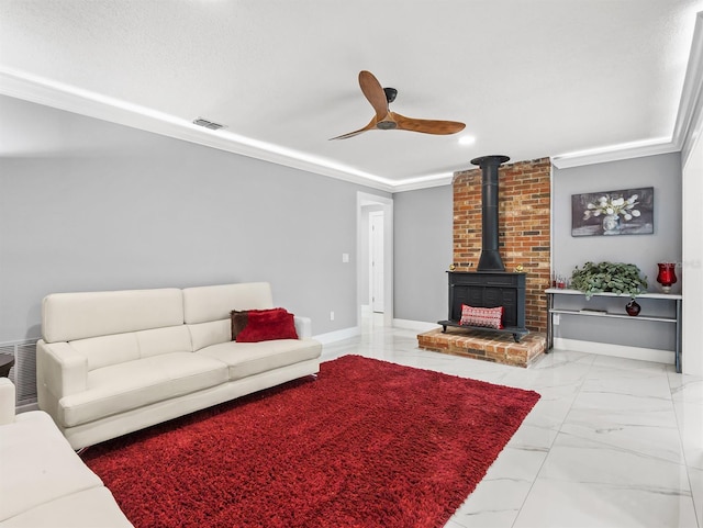 living area featuring visible vents, ceiling fan, ornamental molding, a wood stove, and marble finish floor