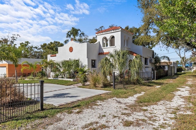 mediterranean / spanish house featuring a tiled roof, driveway, fence, and stucco siding