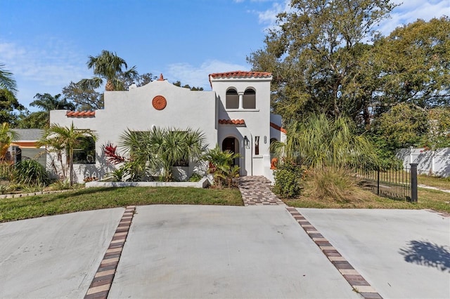 mediterranean / spanish-style home with fence and stucco siding