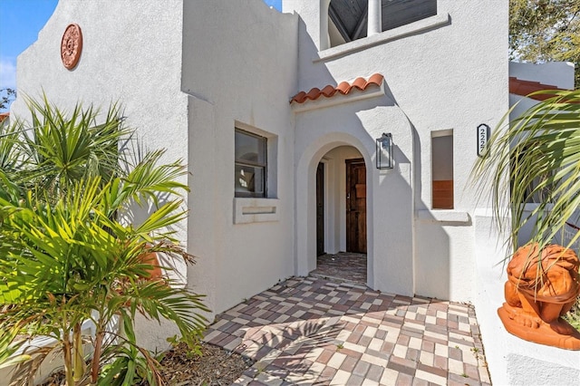 doorway to property with a tiled roof and stucco siding