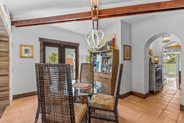 dining area featuring arched walkways, french doors, baseboards, and beam ceiling