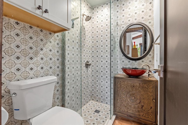 bathroom with a tile shower, vanity, and toilet