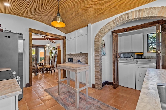 kitchen with arched walkways, independent washer and dryer, backsplash, and white cabinets