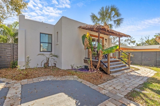 view of front facade with a patio area, fence, and stucco siding