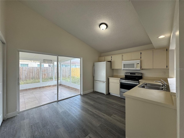 kitchen featuring white appliances, lofted ceiling, dark wood-style floors, light countertops, and a sink