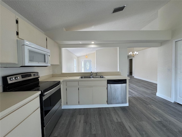 kitchen featuring stainless steel appliances, a sink, visible vents, vaulted ceiling, and light countertops