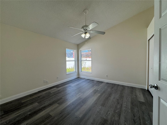 empty room featuring dark wood-type flooring, vaulted ceiling, a textured ceiling, and baseboards