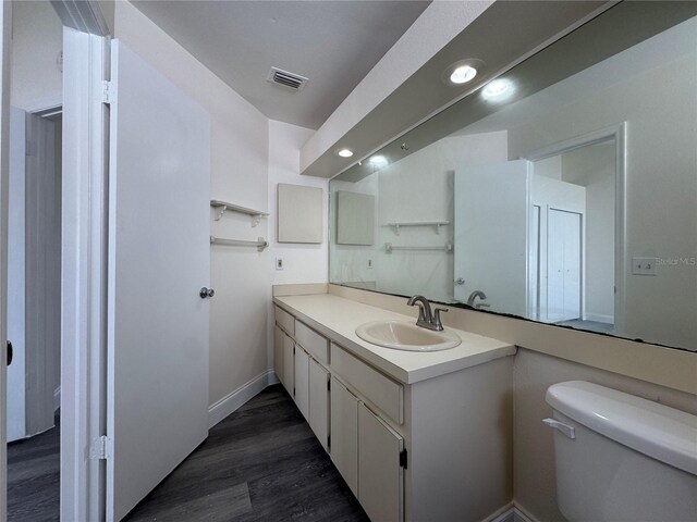 bathroom with baseboards, visible vents, toilet, wood finished floors, and vanity