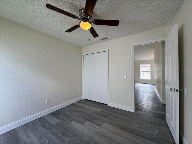 unfurnished bedroom with dark wood-type flooring, visible vents, a textured ceiling, and baseboards