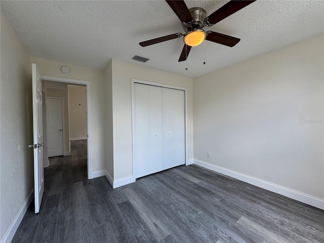 unfurnished bedroom with a closet, dark wood finished floors, visible vents, and baseboards