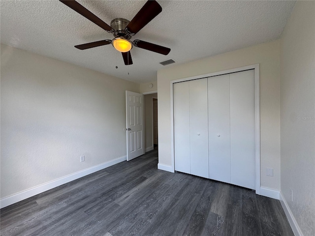 unfurnished bedroom with dark wood-style floors, a closet, visible vents, a textured ceiling, and baseboards