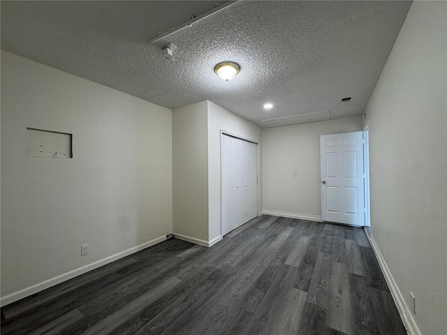 unfurnished room featuring baseboards, a textured ceiling, visible vents, and dark wood-style flooring