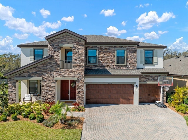 view of front facade featuring a shingled roof, decorative driveway, an attached garage, and stucco siding