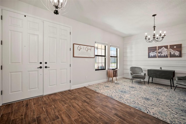 entryway featuring baseboards, dark wood-type flooring, and an inviting chandelier