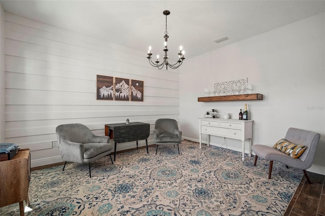 living area featuring visible vents, a notable chandelier, baseboards, and wood finished floors