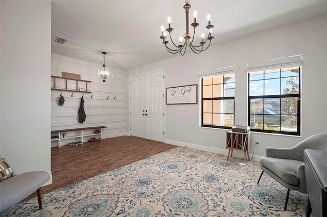 mudroom with baseboards, wood finished floors, visible vents, and a notable chandelier