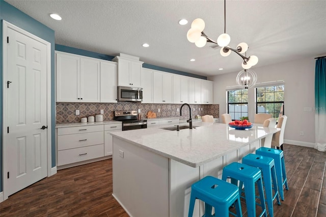 kitchen with appliances with stainless steel finishes, backsplash, a sink, and an inviting chandelier