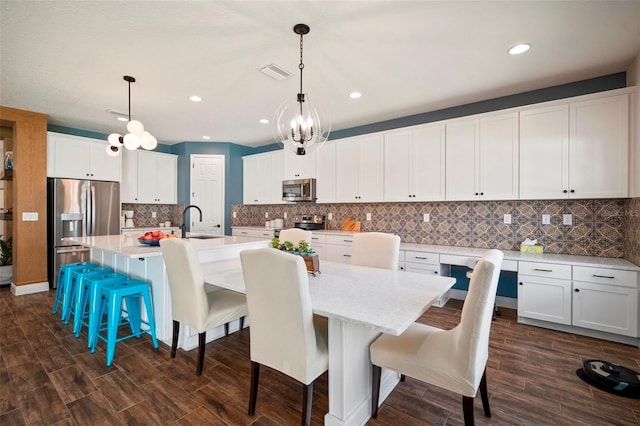 kitchen with a spacious island, visible vents, appliances with stainless steel finishes, dark wood-type flooring, and white cabinetry