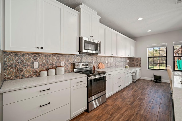 kitchen with dark wood finished floors, appliances with stainless steel finishes, light countertops, white cabinetry, and backsplash