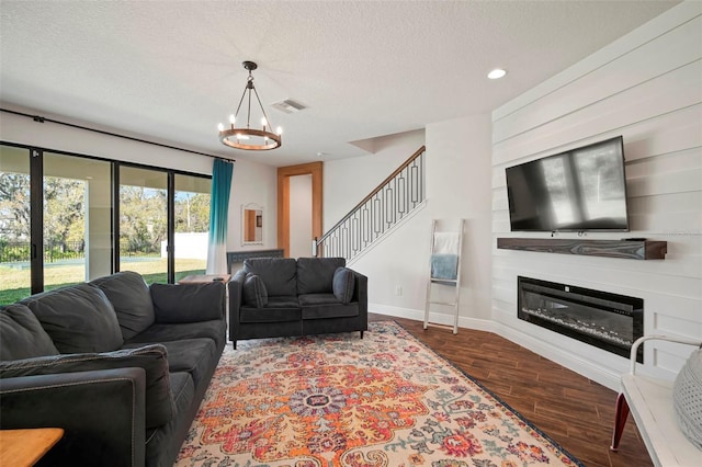 living area featuring a textured ceiling, visible vents, wood finished floors, and a glass covered fireplace