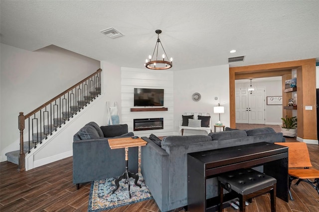 living area featuring wood tiled floor, a large fireplace, visible vents, and stairs