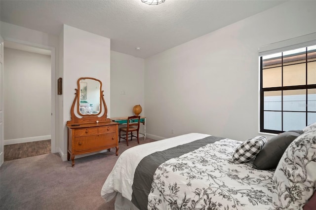 carpeted bedroom featuring a textured ceiling and baseboards