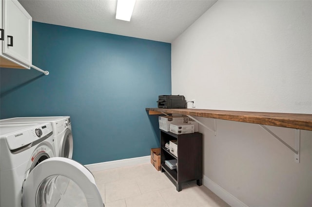 laundry area featuring cabinet space, baseboards, a textured ceiling, washing machine and dryer, and light tile patterned flooring