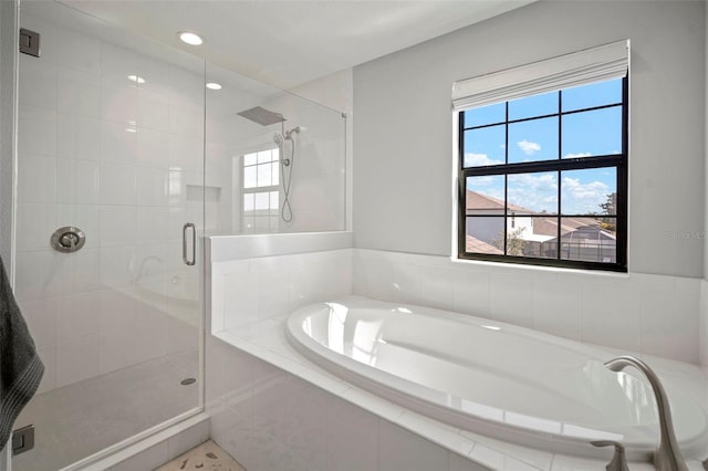 bathroom featuring a shower stall, a bath, and a healthy amount of sunlight