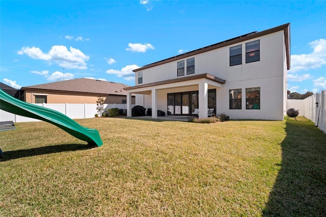 back of house featuring a fenced backyard, a playground, a lawn, and stucco siding