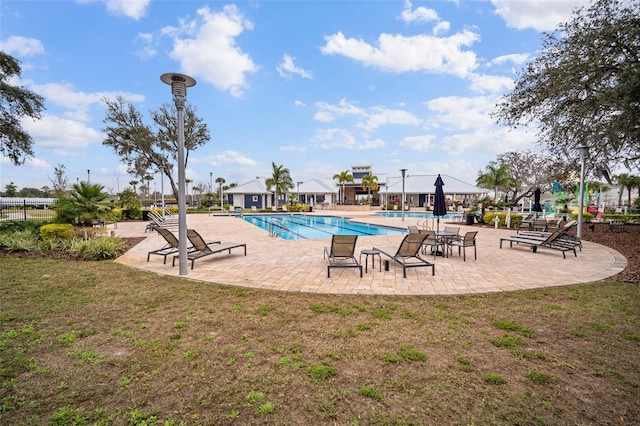 community pool with fence, a lawn, and a patio