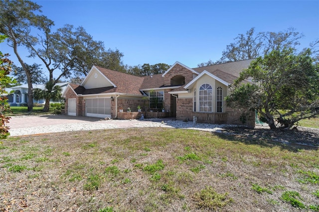 view of front of house with an attached garage, driveway, a front lawn, and brick siding