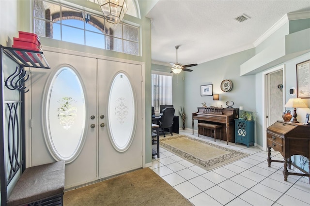 foyer entrance with light tile patterned floors, a textured ceiling, visible vents, ornamental molding, and a wealth of natural light