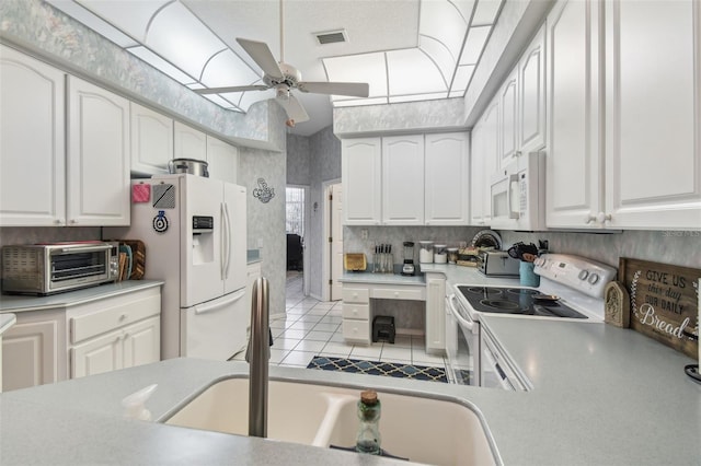 kitchen featuring white appliances, a toaster, and white cabinets